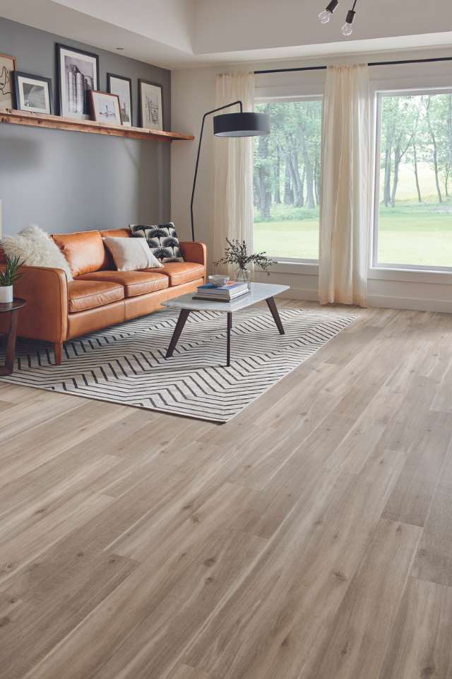 wood-look resilient flooring in modern living room with leather couch and geometric rug